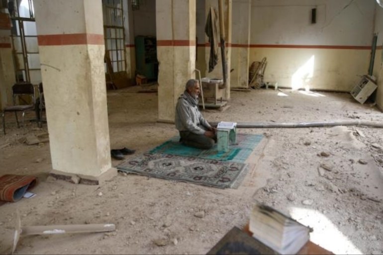 东古塔地区的一名叙利亚人正在被毁的清真寺中读《古兰经》 [路透社]