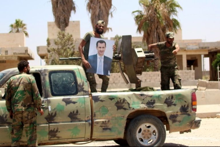 A Syrian soldier holds up a photo of Syrian President Bashar Assad at Nassib border crossing in the southeastern countryside of Daraa city
