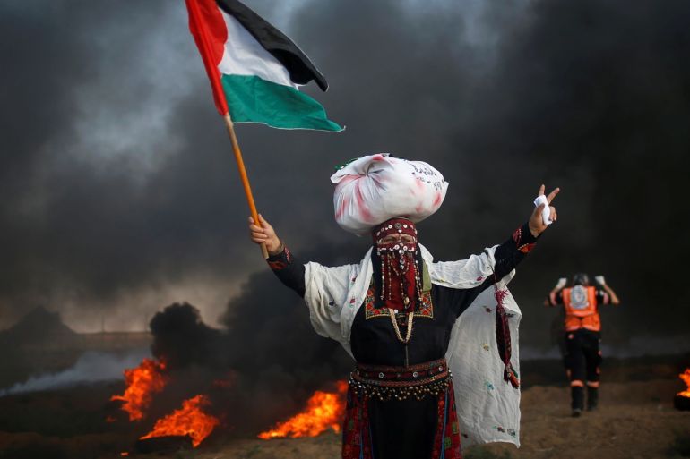 A woman holds a Palestinian flag during a protest calling for lifting the Israeli blockade on Gaza and demand the right to return to their homeland, at the Israel-Gaza border fence, east of Gaza City September 14, 2018. REUTERS/Mohammed Salem