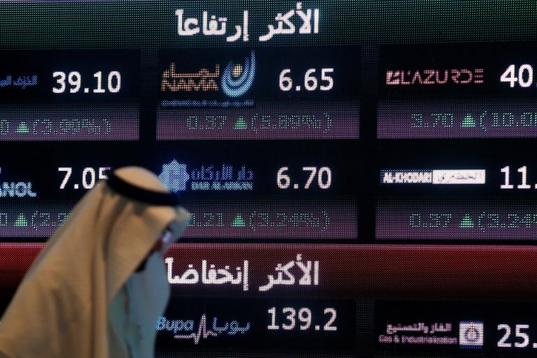 An investor walks past a screen displaying stock information at the Saudi Stock Exchange (Tadawul) in Riyadh, Saudi Arabia June 29, 2016. REUTERS/Faisal Al Nasser