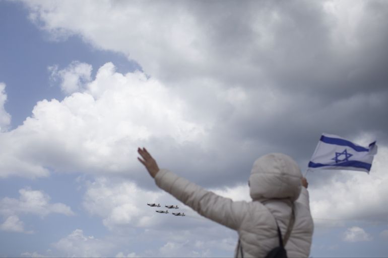 TEL AVIV, ISRAEL - APRIL 23: An Israeli woman waves with an Israeli flag near the Mediterranean sea while watching a military air show marking the 67th anniversary of Israel's independence on April 23, 2015 in Tel Aviv, Israel. The day marks when David Ben-Gurion, the Executive Head of the World Zionist Organization declared the establishment of a Jewish state in Eretz- Israel. (Photo by Lior Mizrahi/Getty Images)