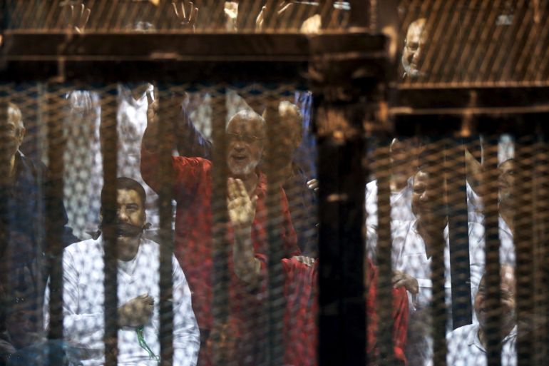 Mohamed Badie (C, in red), the general guide of the Muslim Brotherhood, and other Muslim Brotherhood members gesture behind bars after their verdict at a court on the outskirts of Cairo, Egypt June 16, 2015. An Egyptian court sentenced deposed President Mohamed Mursi to death on Tuesday on charges of killing, kidnapping and other offences during a 2011 mass jail break.The general guide of the Muslim Brotherhood, Mohamed Badie, and four other Brotherhood leaders were als