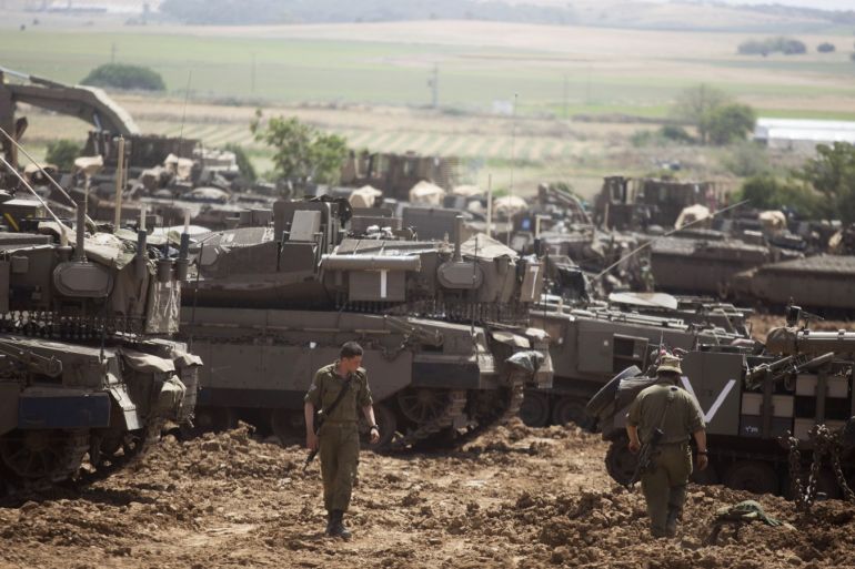 MAVKIM, ISRAEL - MAY 06: Israeli soldiers walks in front of a Merkava tanks, stationed near the border with the Gaza Strip on May 6, 2019 in Mavkim, Israel. Palestinian leaders in Gaza agreed a ceasefire with Israel on today to end a deadly two-day escalation in violence that threatened to widen into war. (Photo by Lior Mizrahi/Getty Images)