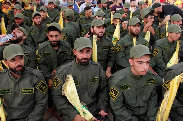 Lebanon's Hezbollah members hold party flags as they listen to their leader Sayyed Hassan Nasrallah addressing his supporters via a screen during a rally marking the anniversary of the defeat of militants near the Lebanese-Syrian border, in al-Ain village, Lebanon August 25, 2019. REUTERS/Aziz Taher