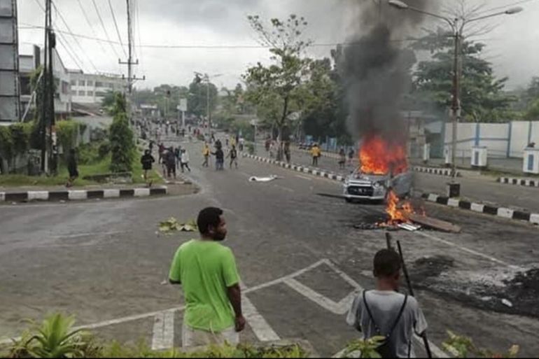 epa07780429 People gather as a car burns during a violent protest in Manokwari West Papua Province, Indonesia, 19 August 2019. According to media reports, protesters set on fire the local parliament building and cars during a protest against the detention of Papuan students for damaging a national flag pole outside of a dormitory for Papuan students in Surabaya EPA-EFE/SOFWAN AZHARI -- BEST QUALITY AVAILABLE
