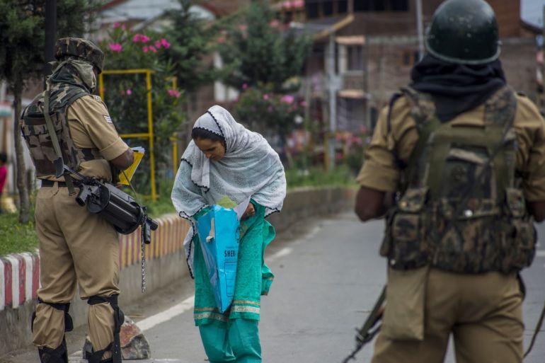 Indian government forces check the prescriptions of a woman before allowing her to walk towards the hospital