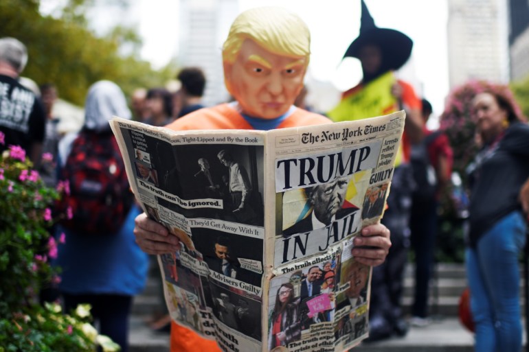 A man wearing a mask in the image of of U.S. President Donald Trump pretends to read a fake newspaper ahead of a protest against Trump on the sidelines of the United Nations General Assembly in New York, U.S., September 23, 2019. REUTERS/Mark Kauzlarich