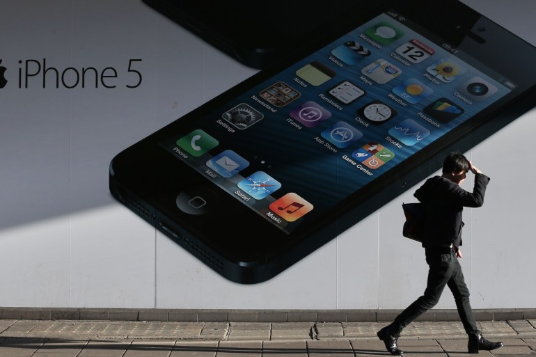 LONDON, ENGLAND - DECEMBER 17: A shopper walks past a giant advertisment for the Apple iPhone 5 near Oxford Street on December 17, 2012 in London, England. Thousands of shoppers are expected in London's west end in the hunt for Christmas bargains in the next week. (Photo by Peter Macdiarmid/Getty Images)