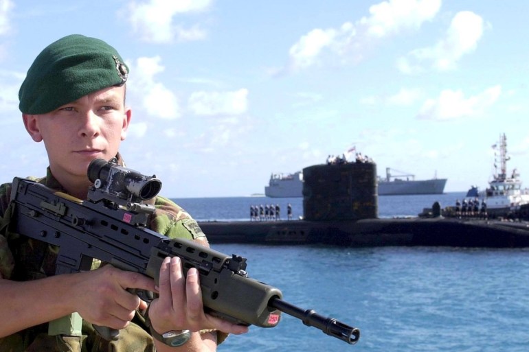 MOD02 - 20011116 - DIEGO GARCIA, BRITISH INDIAN OCEAN TERRITORY : Picture released 16 November 2001 by the British Ministry of Defence, shows a Royal Marine commando guarding a Royal Navy T class submarine arriving at the Diego Garcia US Navy base. According to newspapers reports in the UK quoting diplomatic an defence sources, the deployment of thousands of British troops in Afghanistan is deing delayed because of divisions between London and Washington over their precise role. EPA PHOTO MOD/MOD/
