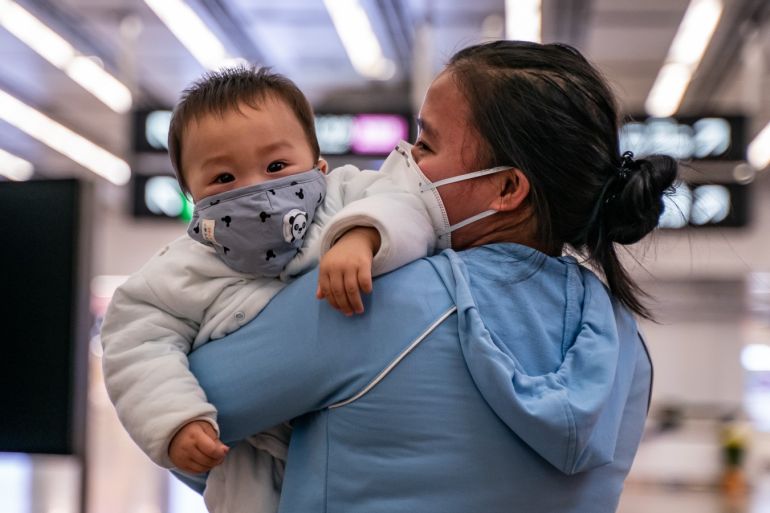 HONG KONG, CHINA - JANUARY 29: A woman carries a baby wearing a protective mask as they exit the arrival hall at Hong Kong High Speed Rail Station on January 29, 2020 in Hong Kong, China. Hong Kong government will deny entry for travellers who has been to Hubei province except for local residents in response to tighten the international travel and border crossing to stop the spread of the virus. (Photo by Anthony Kwan/Getty Images)
