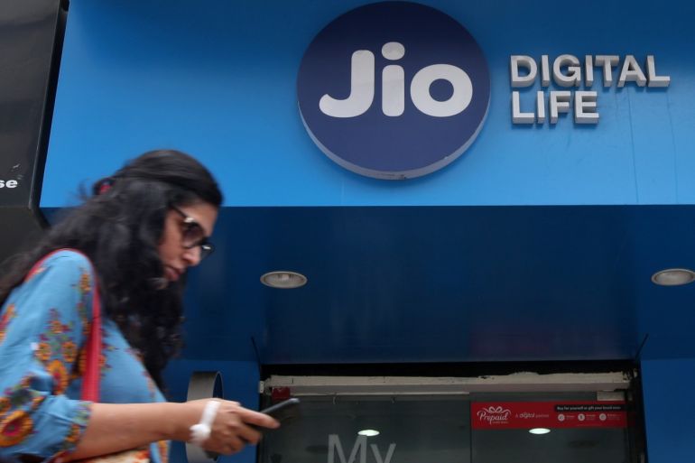 A woman checks her mobile phone as she walks past a mobile store of Reliance Industries' Jio telecoms unit, in Mumbai, India, July 11, 2017. REUTERS/Shailesh Andrade