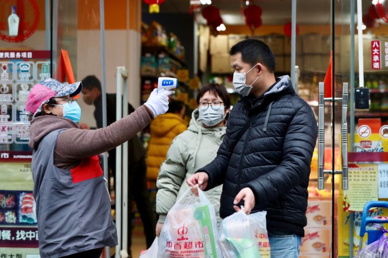 A worker measures body temperature of people leaving a supermarket in Qingshan district following an outbreak of the novel coronavirus in Wuhan, Hubei province, China February 7, 2020. Picture taken February 7, 2020. China Daily via REUTERS ATTENTION EDITORS - THIS IMAGE WAS PROVIDED BY A THIRD PARTY. CHINA OUT.