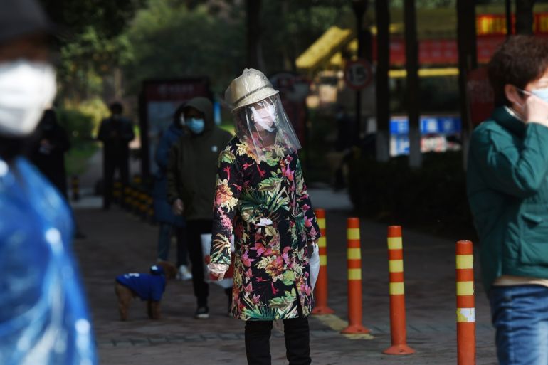 A resident wearing makeshift protective face shield stands in a line to collect food and necessities purchased through group orders at an entrance to a residential compound in Wuhan, the epicentre of the novel coronavirus outbreak, Hubei province, China February 21, 2020. REUTERS/Stringer CHINA OUT.
