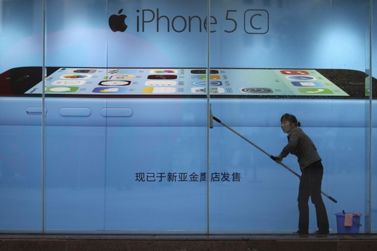 A worker cleans glass in front of an iPhone