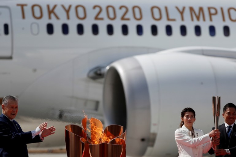 Three-time Olympic gold medalists Tadahiro Nomura and Saori Yoshida pose after lighting the Olympic Flame at the Olympic cauldron while watched by Tokyo 2020 Olympics President Yoshiro Mori (L) during a ceremony at Japan Air Self-Defense Force Matsushima Base in Higashi-Matsushima, Miyagi prefecture, northern Japan March 20, 2020. REUTERS/Issei Kato TPX IMAGES OF THE DAY