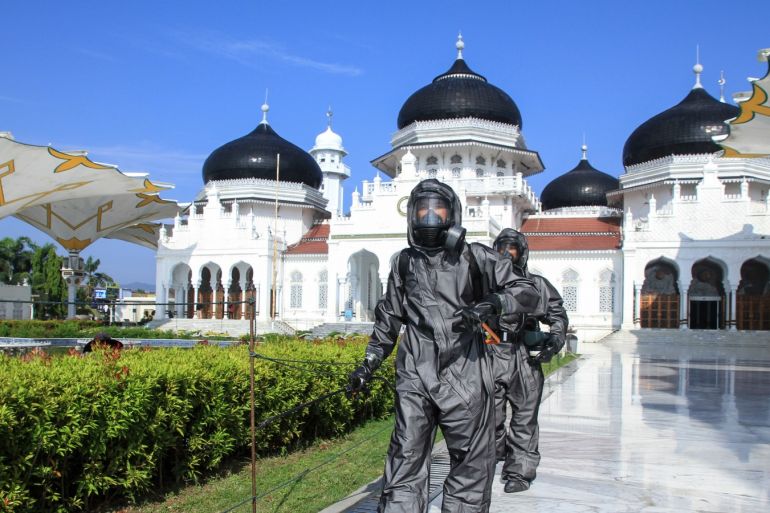 Precaution coronavirus in Aceh, Indonesia- - ACEH, INDONESIA - MARCH 21: Aceh police personnel with protective suit spray disinfectant as a part prevention spread coronavirus (COVID-19) at Baiturrahman Mosque, in Aceh, Indonesia on March 21, 2020.