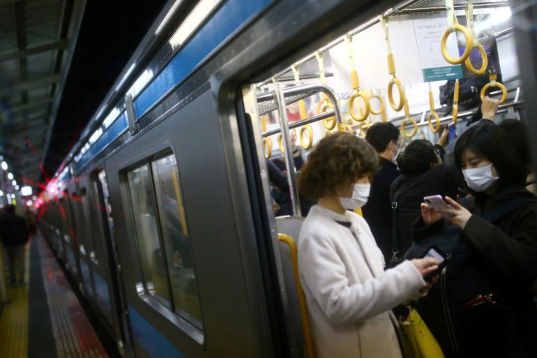 Women, wearing protective face masks following an outbreak of the coronavirus disease (COVID-19), look their mobile phones inside a train at subway station in Kyoto, Japan, March 13, 2020. REUTERS/Edgard Garrido