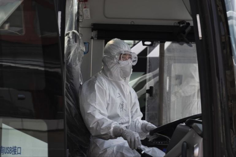 A Chinese bus driver wears a protective white suit as he waits to drive travellers from Wuhan as they are processed and taken to do 14 days of quarantine, after arriving on the first trains to Beijing on April 8, 2020 in Beijing, China.