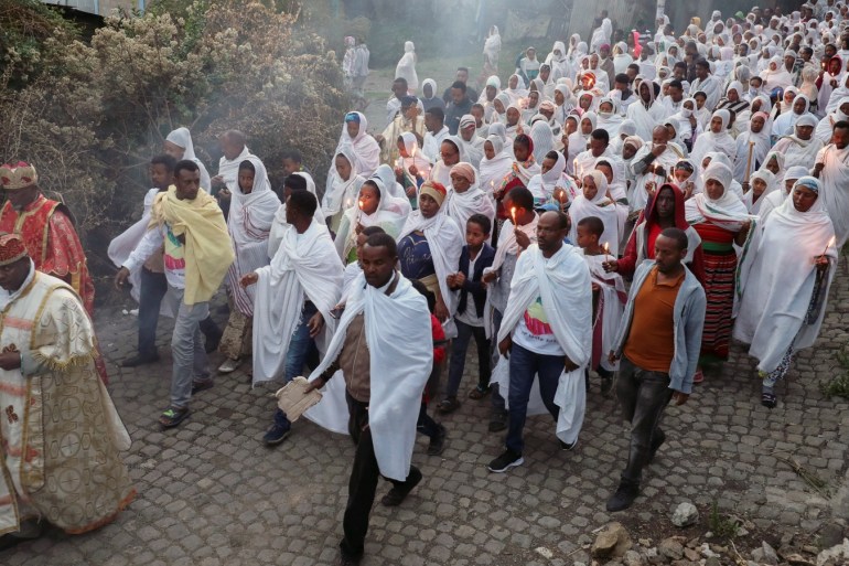 Ethiopian Orthodox faithful hold candles as they receive a blessing from a priest with an incense smoke which according to their belief will keep the coronavirus disease (COVID-19) away, in Addis Ababa, Ethiopia March 26, 2020. REUTERS/Tiksa Negeri TPX IMAGES OF THE DAY