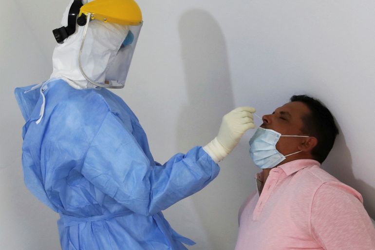 Member of a medical team wearing a protective suit takes a swab to test for the coronavirus disease (COVID-19), in Tripoli