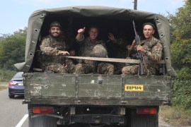 Ethnic Armenian soldiers react as they ride in the back of a truck in Nagorno-Karabakh