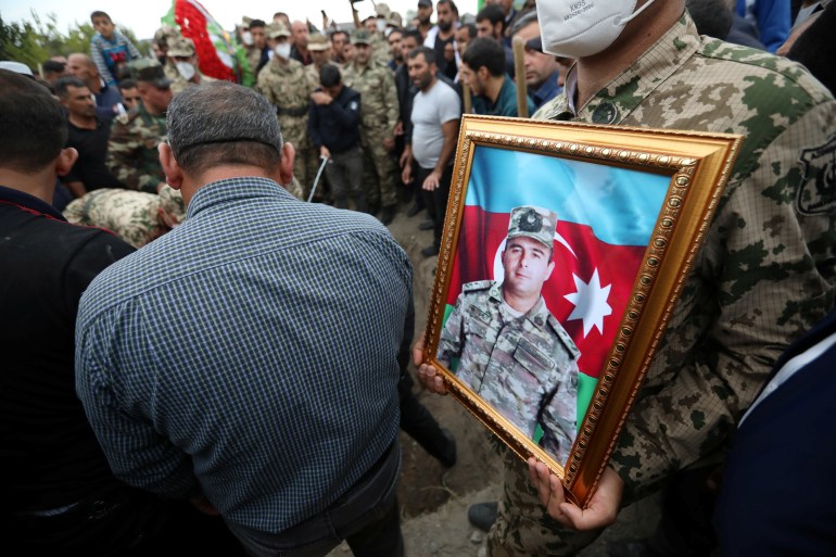 A servicemen holds a portrait of Colonel Lieutenant Makhman Ganbarov, who was killed during the fighting over the breakaway region of Nagorno-Karabakh, during a funeral in the city of Barda