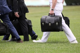 A military aide carries the so-called nuclear football as he walks to board the Marine One helicopter with U.S. President Trump for travel from the White House in Washington