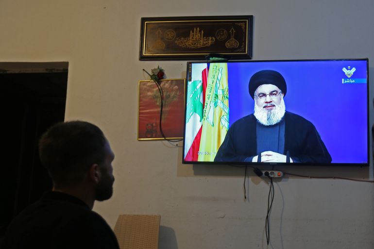 A man watches Lebanon's Hezbollah leader Sayyed Hassan Nasrallah speaking on television, inside a shop in Houla