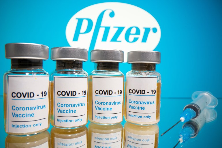 Vials and medical syringe are seen in front of Pfizer logo in this illustration