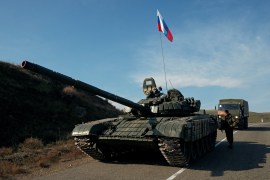 A service member of the Russian peacekeeping troops stands next to a tank in Nagorno-Karabakh