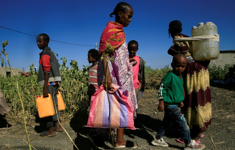 Ethiopian refugees fleeing from the ongoing fighting in Tigray region, carry water jerrycans at the Fashaga camp, on the Sudan-Ethiopia border, in Kassala state