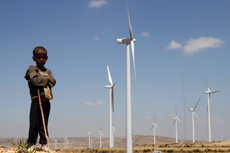 A boy stands in front of wind turbines at the Ashegoda Wind Farm, near a village in Mekelle