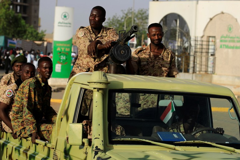 Sudanese soldiers are seen on an army vehicle as they drive through the defense ministry compound in Khartoum