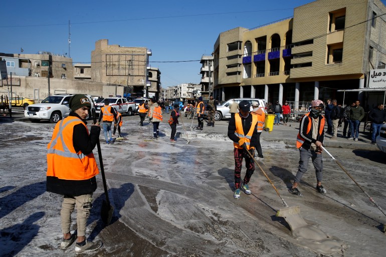 Workers clean the site of a twin suicide bombing attack in a central market in Baghdad