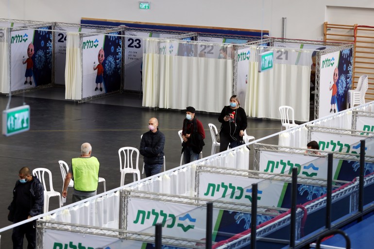 People queue to receive a vaccination against the coronavirus disease (COVID-19) at a temporary Clalit healthcare maintenance organisation (HMO) centre, at a basketball court in Petah Tikva