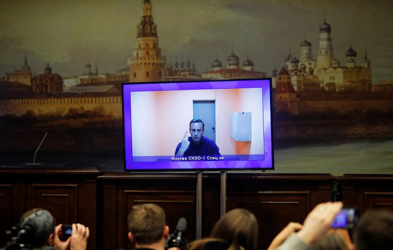 Russian opposition leader Alexei Navalny is seen on a screen via a video link during a court hearing to consider an appeal on his arrest, outside Moscow