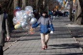 2021年3月13日，一名戴着口罩的男子手持一束气球出现在纽约中央公园附近的第五大道上 (盖帝图像)