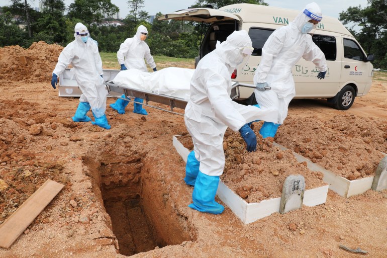 Workers wearing protective suits bury a victim of the coronavirus disease (COVID-19) at a cemetery in Petaling Jaya