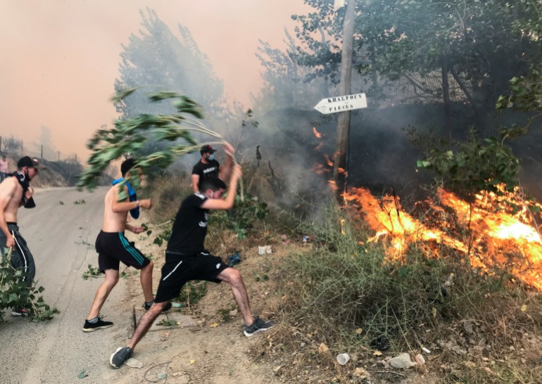 People attempt to put out a fire in the mountainous Tizi Ouzou