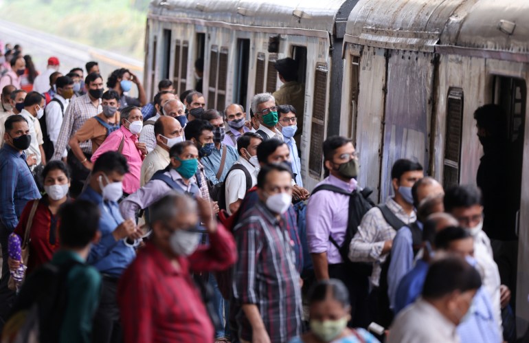 Commuters wearing protective face masks wait to board a suburban train after authorities resumed train services for vaccinated passengers amid the coronavirus disease (COVID-19) pandemic, in Mumbai