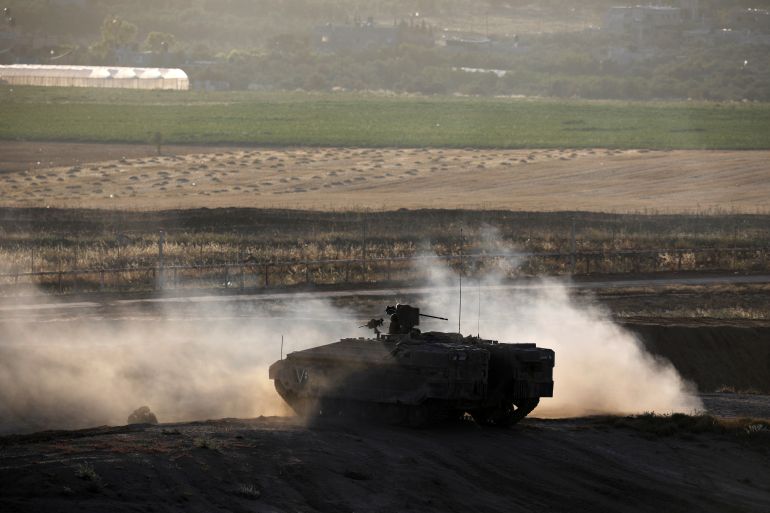 An Israeli armoured personnel carrier (APC) maneuvers on the Israeli side of the border fence between Israel and the Gaza Strip