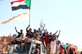 2021 年 12 月 19 日，苏丹青年在首都喀土穆北部反对 10 月 25 日政变的集会中高举国旗，示威随后遭到血腥镇压（法新社）