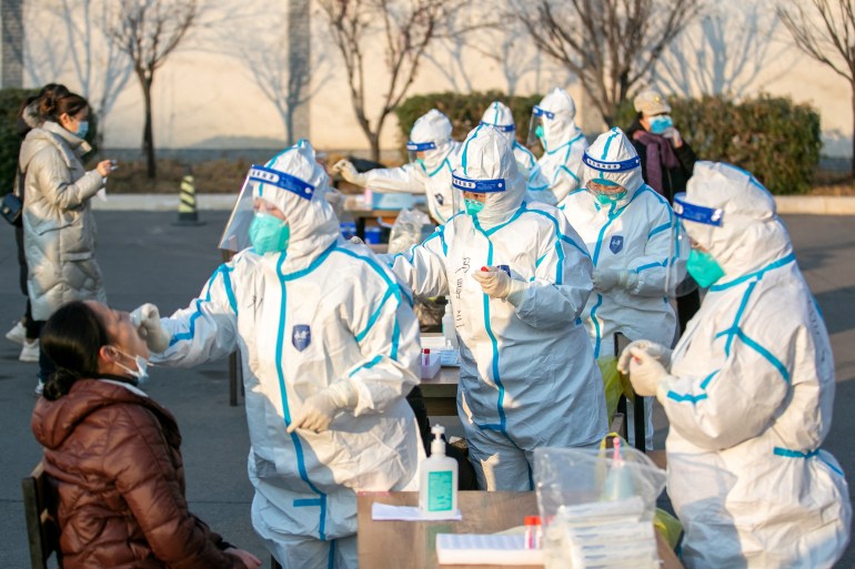 Medical workers in protective suits collect swabs from residents at a nucleic acid testing site in Yuncheng