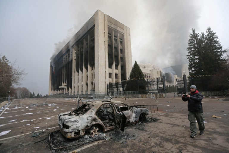 A man takes a picture near the mayor's office building which was torched during protests in Almaty