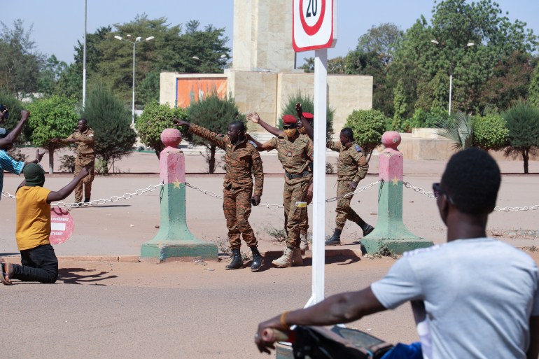 Army soldiers ask people to walk away as they gather outside Guillaume Ouedraogo army camp to show their support for the military after President Kabore was detained at a military camp in Ouagadougou