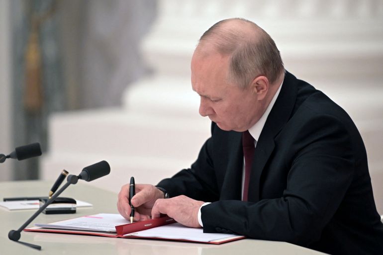 Russian President Vladimir Putin signs a decree recognising two Russian-backed breakaway regions in eastern Ukraine as independent entities during a ceremony in Moscow
