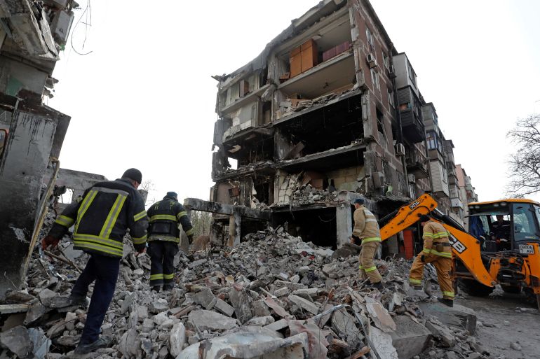 Rescuers work at a damaged residential building in Mariupol