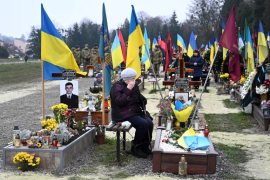 2022 年 12 月 6 日，乌克兰建军节期间，在乌克兰西部城市利沃夫利查基夫公墓，一名老妇人在一名乌克兰士兵的坟墓旁哀悼（法新社）