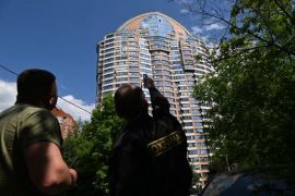 在有消息称莫斯科发生无人机袭击事件后，一名安保人员指着一栋多层公寓楼