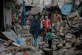 2023年11月27日，加沙城Al-Zawiya市场附近，巴勒斯坦人在以色列袭击中遭到袭击的建筑物废墟中行走 (AFP)